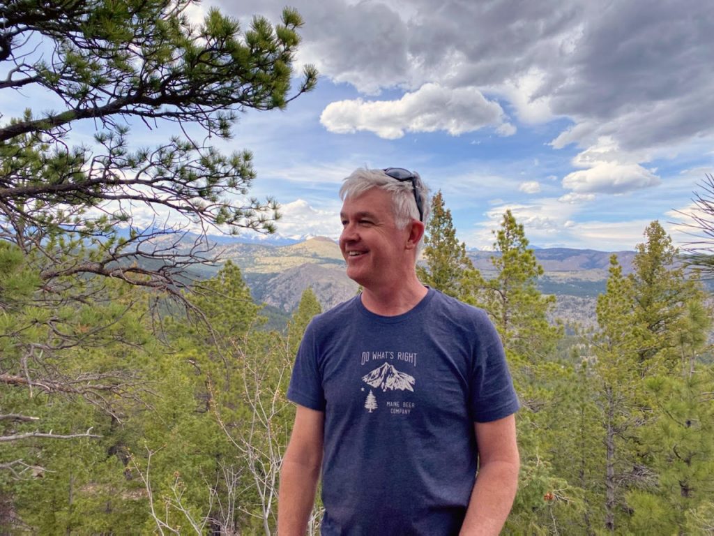 Brian Buckley standing overlooking the Colorado scenery of trees and mountains.